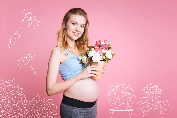フラワー ポットを保持している陽気な妊娠中の女性 — ストック写真