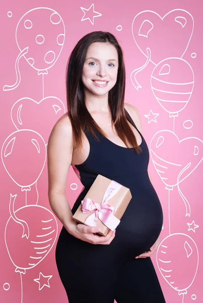 Mulher grávida positiva segurando presente — Fotografia de Stock