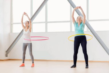Positive active women rotating hula hoops clipart