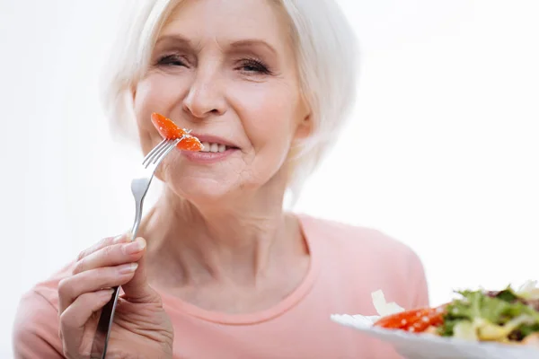 Retrato de mulher idosa enquanto come tomate — Fotografia de Stock