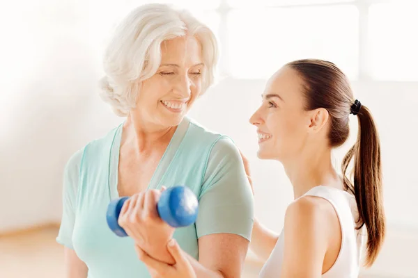 Buen entrenador de fitness ayudando a la anciana —  Fotos de Stock