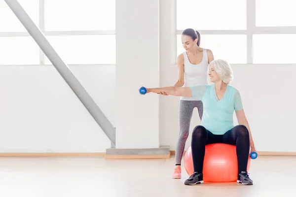 Glada äldre kvinna sitter på en fitness boll — Stockfoto