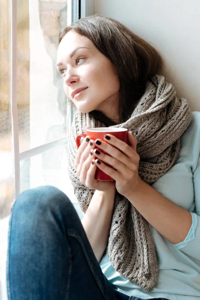Pensativo joven bebiendo té en el alféizar de la ventana — Foto de Stock