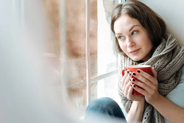 Relajada joven bebiendo té caliente en la ventana — Foto de Stock