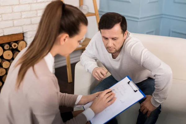 Terapeuta profesional de buen aspecto explicando sus notas — Foto de Stock