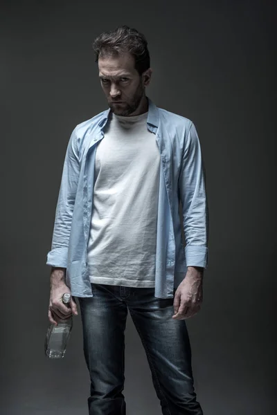 Portrait of severe male person keeping glass bottle — Stock Photo, Image