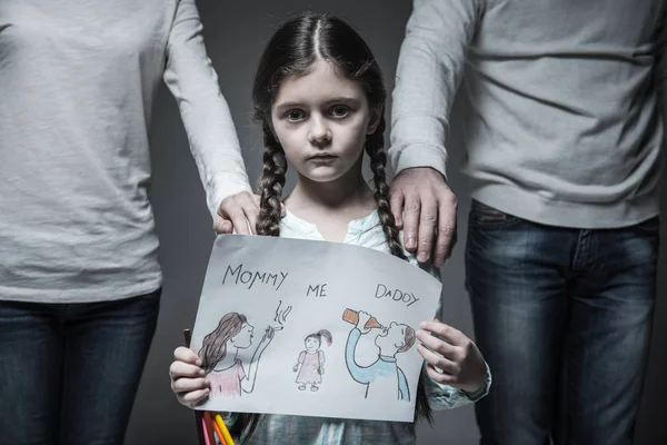 Маленькая грустная девочка, стоящая между родителями — стоковое фото