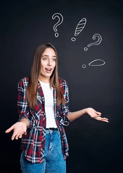 Puzzled woman standing on black background — Stock Photo, Image