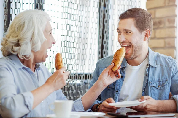 Radosny wieku kobieta i wnuk jeść placki w kawiarni — Zdjęcie stockowe