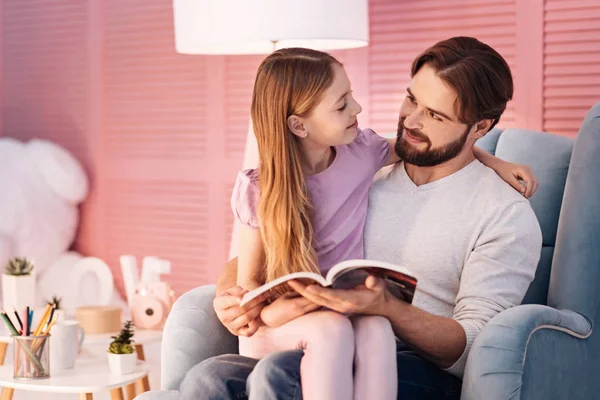 man sitting on sofa and embracing daughte