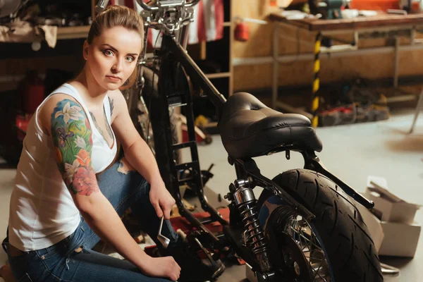 Jovem mulher séria enquanto se senta perto de sua bicicleta — Fotografia de Stock