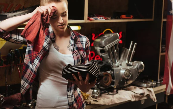 Tired pretty female looking at spare part — Stock Photo, Image