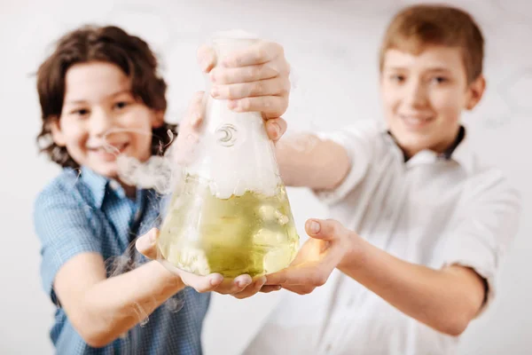 Niños sonriendo y sosteniendo un frasco químico — Foto de Stock