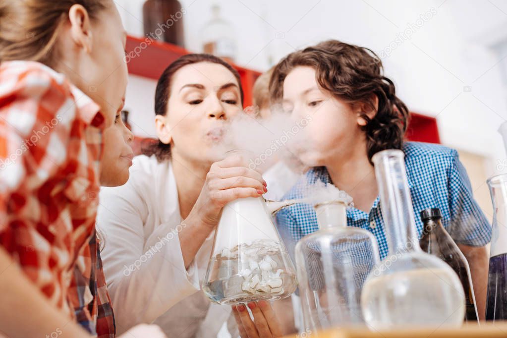 Children blowing on chemical flask