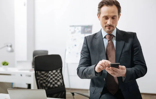Позитивный бизнесмен пользуется телефоном в офисе — стоковое фото