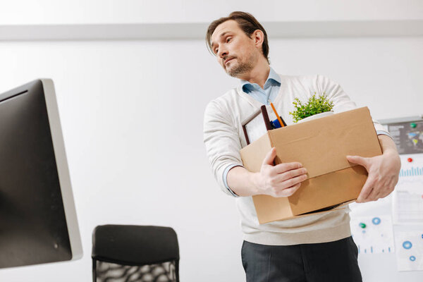 Fired employee carrying the box and leaving the office