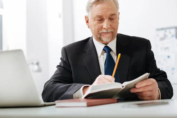 Fleißiger älterer Arbeitgeber überprüft Notizen bei der Arbeit — Stockfoto