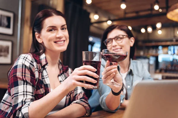 Retrato de mujer positiva mientras tintinea gafas con su amigo — Foto de Stock