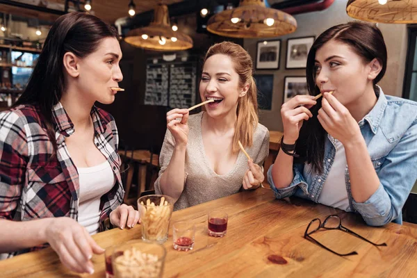 Sonrientes mujeres jóvenes comiendo papas favoritas — Foto de Stock