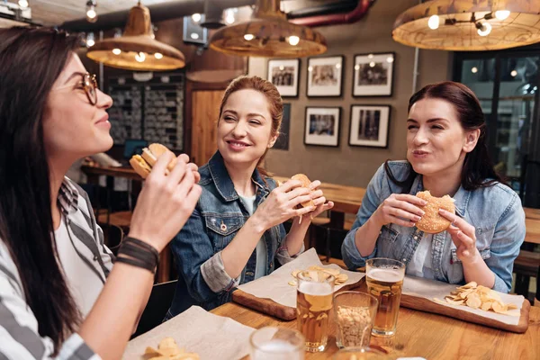 Positieve vrienden zitten met de mond vol van voedsel — Stockfoto