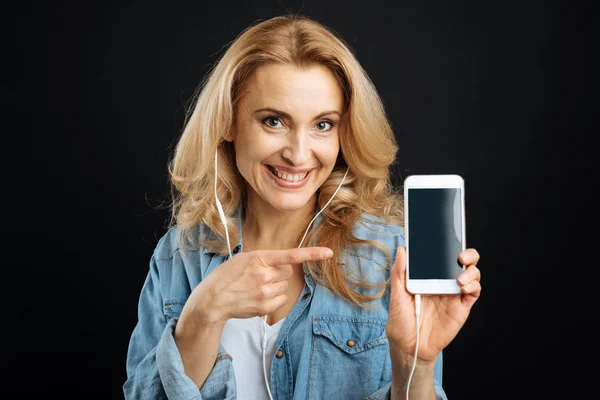 O femeie veselă care prezintă un telefon nou — Fotografie, imagine de stoc