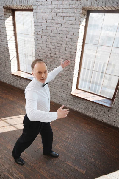 Capable bearded aged man learning classical dance at the ballroom