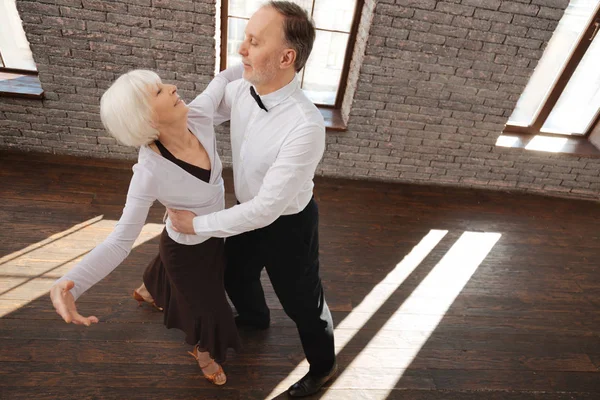 Веселая пожилая пара вальсирует в бальном зале — стоковое фото