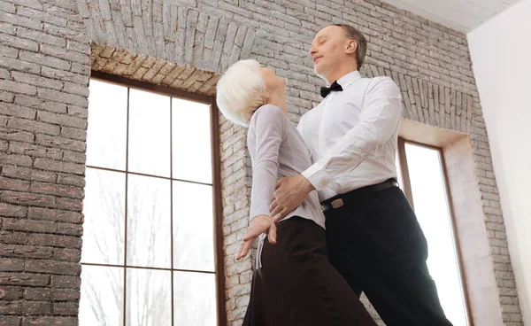 Cute delighted aging couple waltzing in the ballroom — Stock Photo, Image