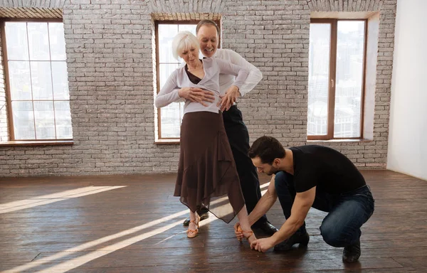 Helpful mature dance instructor teaching aged couple in the ballroom — Stock Photo, Image