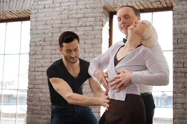 Instruktor tańca uprzejmy nauczania pary staruszków w sali balowej — Zdjęcie stockowe
