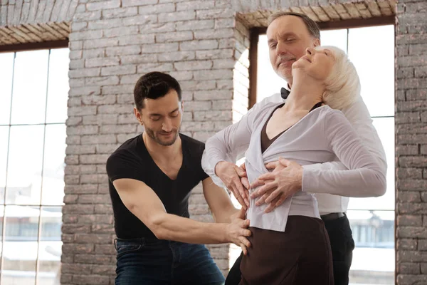 Attentive dance instructor teaching elderly couple in the ballroom — Stock Photo, Image