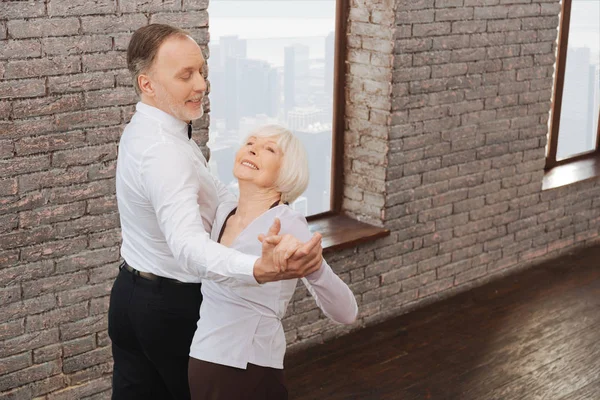 Восхитительные пенсионеры вальсируют в танцевальной студии — стоковое фото