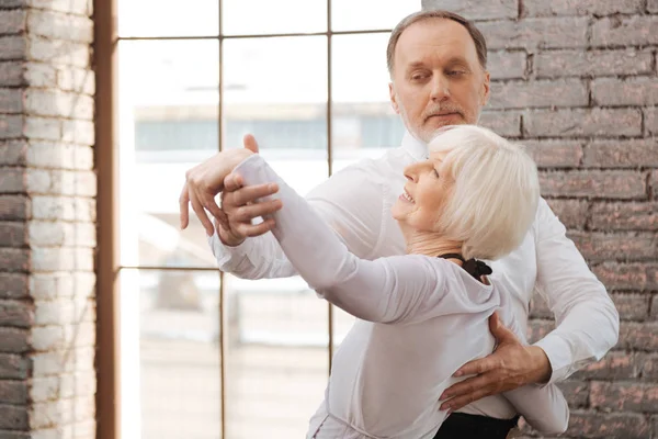 Smiling aged couple performing in interaction in the dance studio