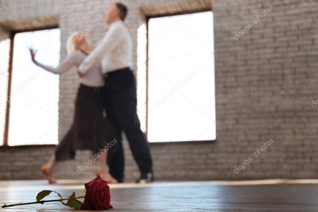 Flexible aged dance couple tangoing at the ballroom