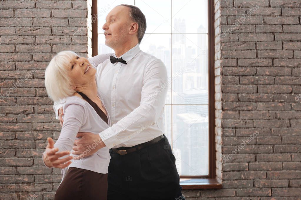 Lively elderly dance couple enjoying tango at the ballroom