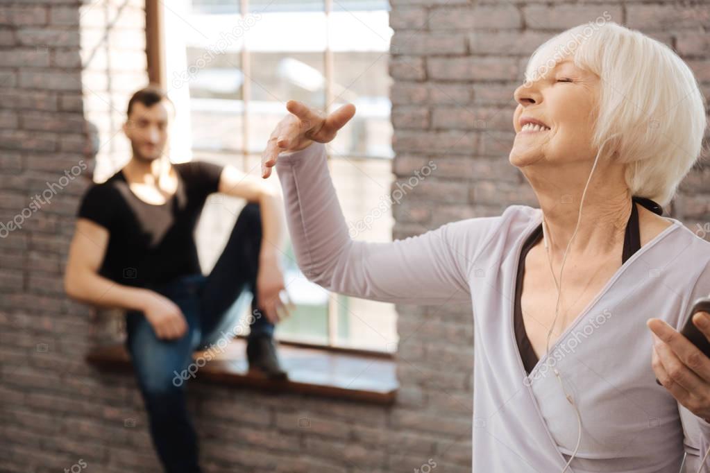 Delighted retired woman enjoying music during the dance class