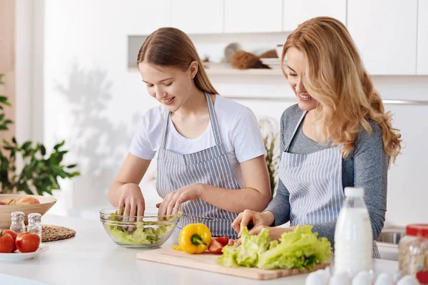 Chica positiva y su madre disfrutando de cocinar juntos — Foto de Stock