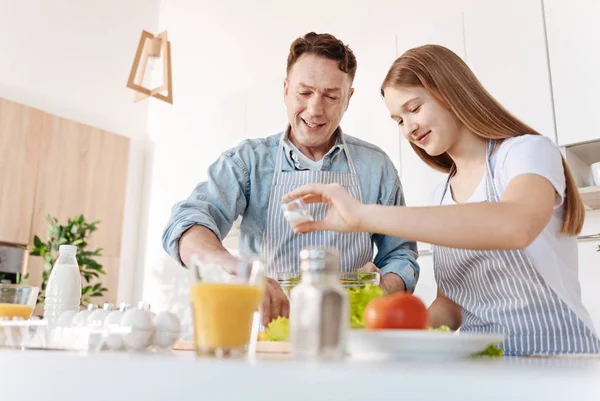 Positiv tjej och hennes carign far matlagning grönsakssallad — Stockfoto