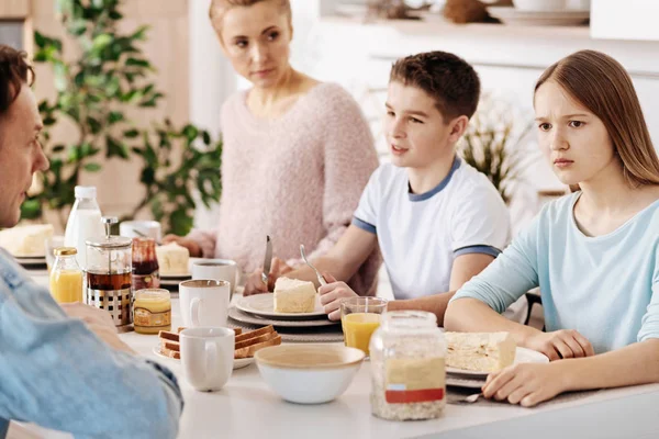 Összezavarodott lány reggelizik a családjával — Stock Fotó