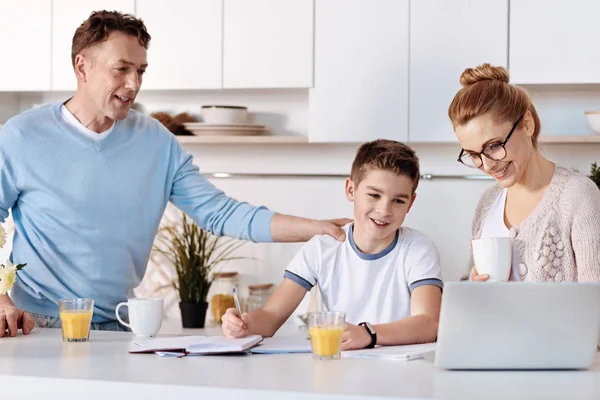 Позитивные родители помогают сыну с домашним заданием — стоковое фото