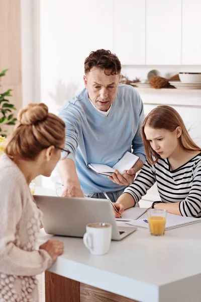 Pleasant girl doing homework with her parents — Stock Photo, Image