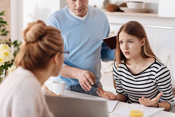 Verdrietig meisje huiswerk met haar ouders — Stockfoto