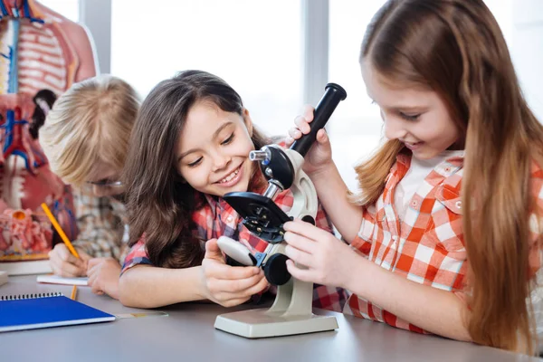 Emocionados compañeros de clase creativos probando un microscopio — Foto de Stock