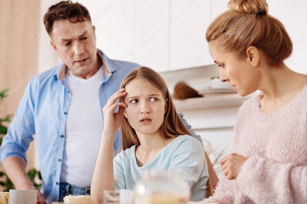Cheerless moody girl discussing problems with her parents