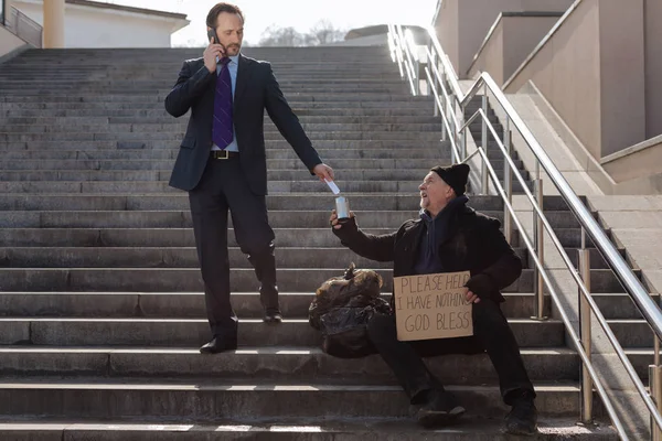 Successful businessman giving money to poor man — Stock Photo, Image