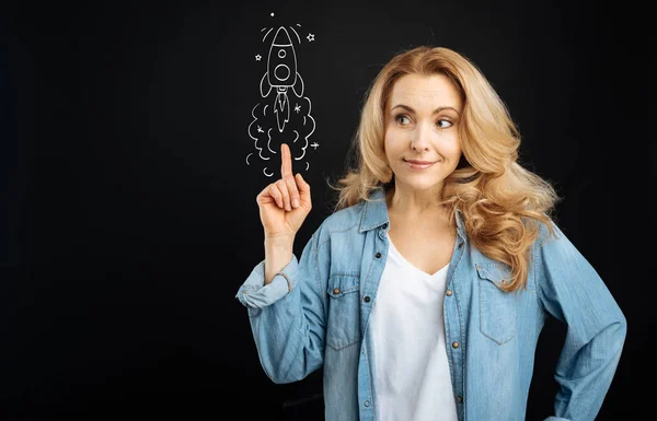 Pleasant cute woman pointing at the rocket — Stock Photo, Image