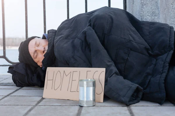 Homem sem-teto deitado no pavimento frio — Fotografia de Stock