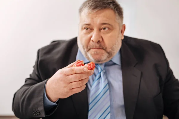 Hungry amusing office worker chewing a doughnut — Stock Photo, Image