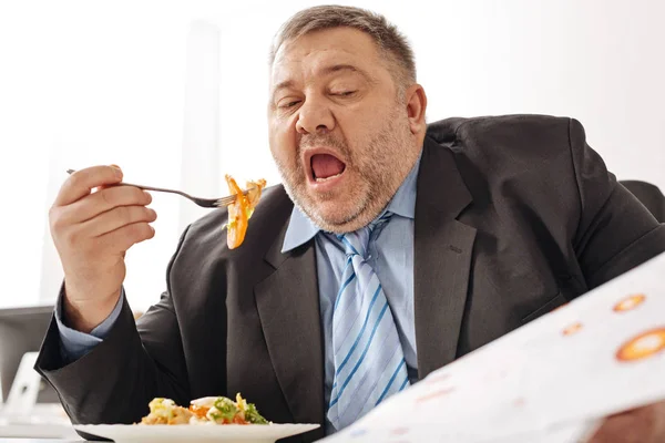 Hardworking tireless employee working a eating at the same time — Stock Photo, Image