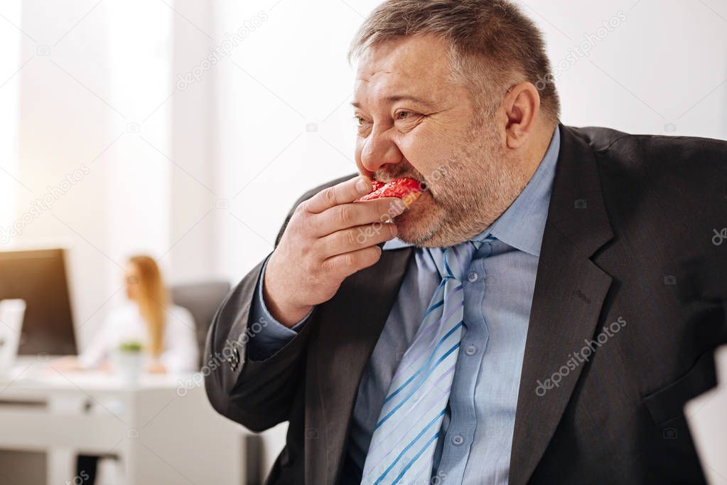 Compulsive immoderate guy engulfing junk food